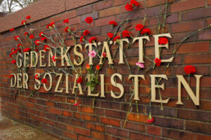 Ein Foto der großen Aufschrift "Gedenkstätte der Sozialisten" an der Gedenkstätte der Sozialisten in Berlin. Die Aufschrift ist anlässlich des Gedenktages an den Mord an Rosa Luxemburg und Karl Liebknecht mit zahlreichen Blumen von Besuchern beschmückt.